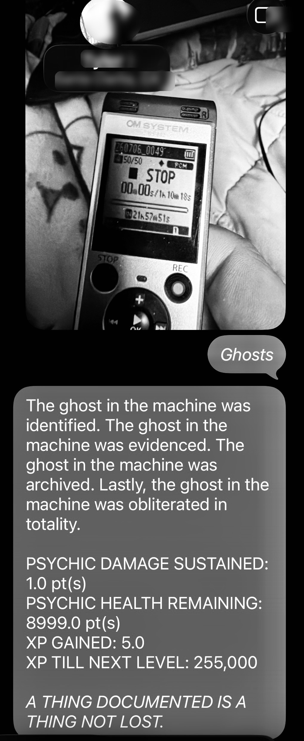 Black-and-white screenshot of a message exchange showing a portable OM System recorder in STOP mode and a gray text bubble describing a ghost-in-the-machine incident.